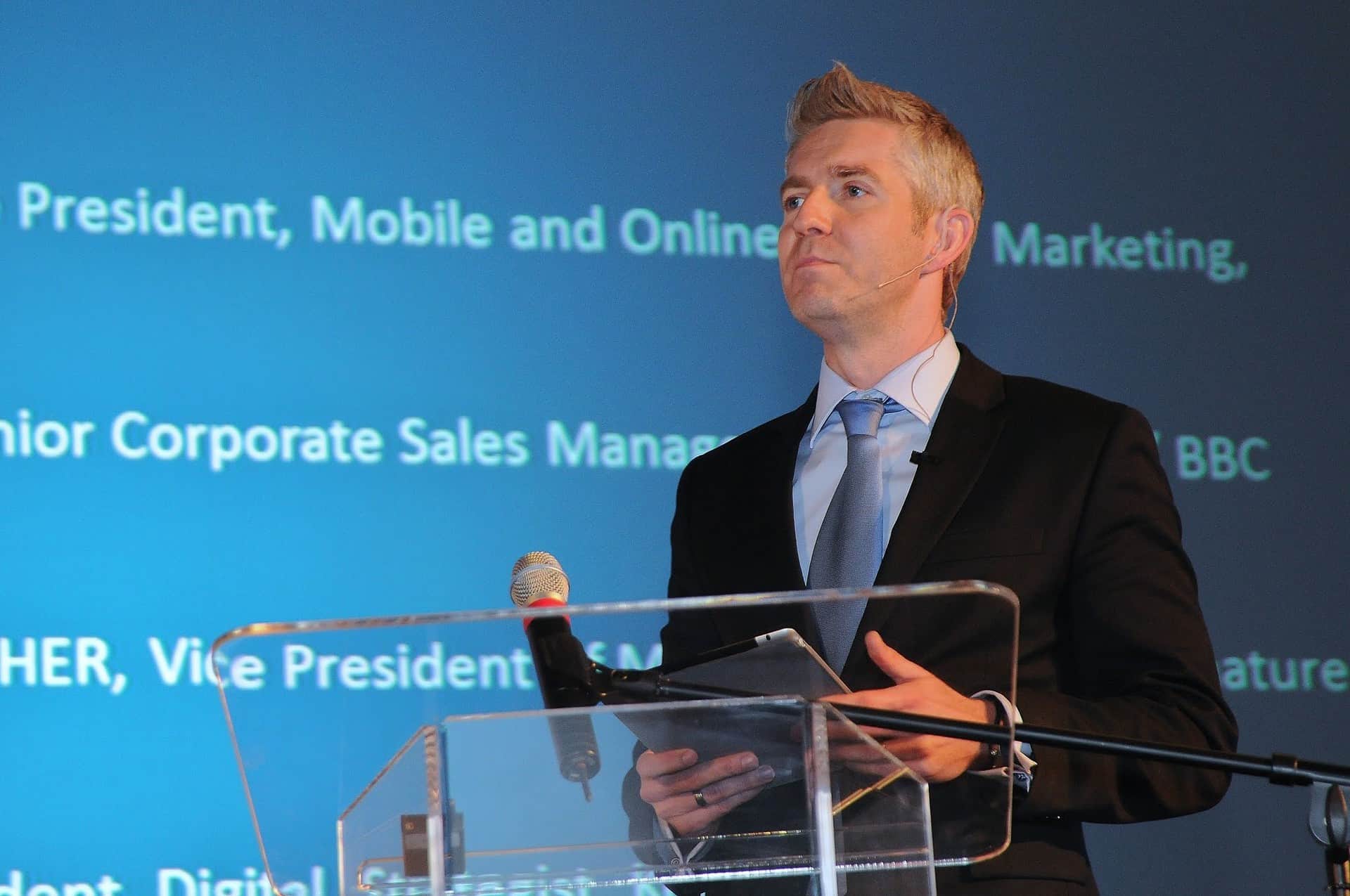 Man speaking into microphone in front of podium