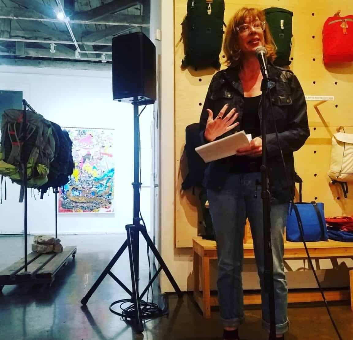 Woman speaking into microphone with speaker in background