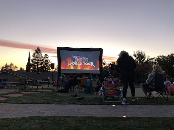 Kids watching outdoor movie while sun sets