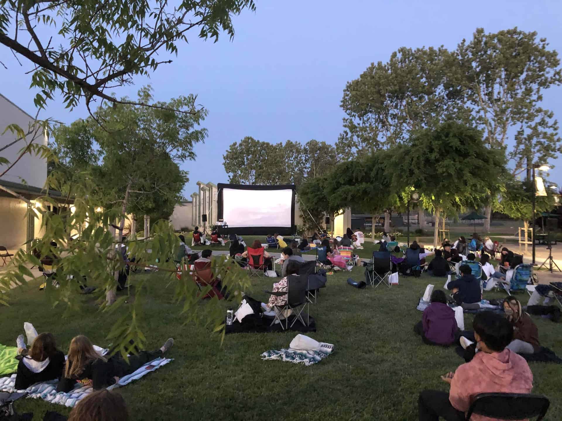 students watching outdoor movie on campus