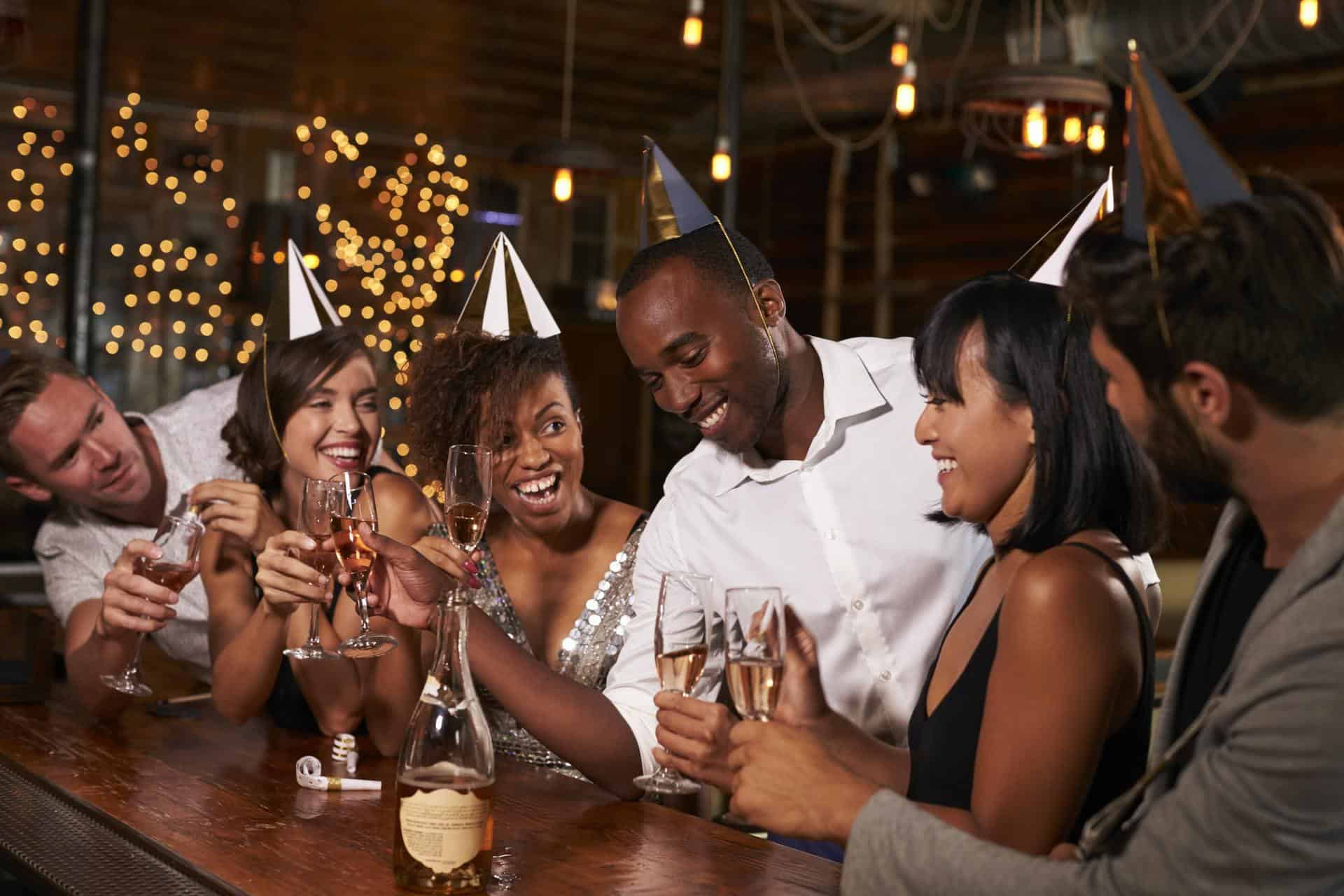 Friends in party hats celebrating New Year at party in a bar