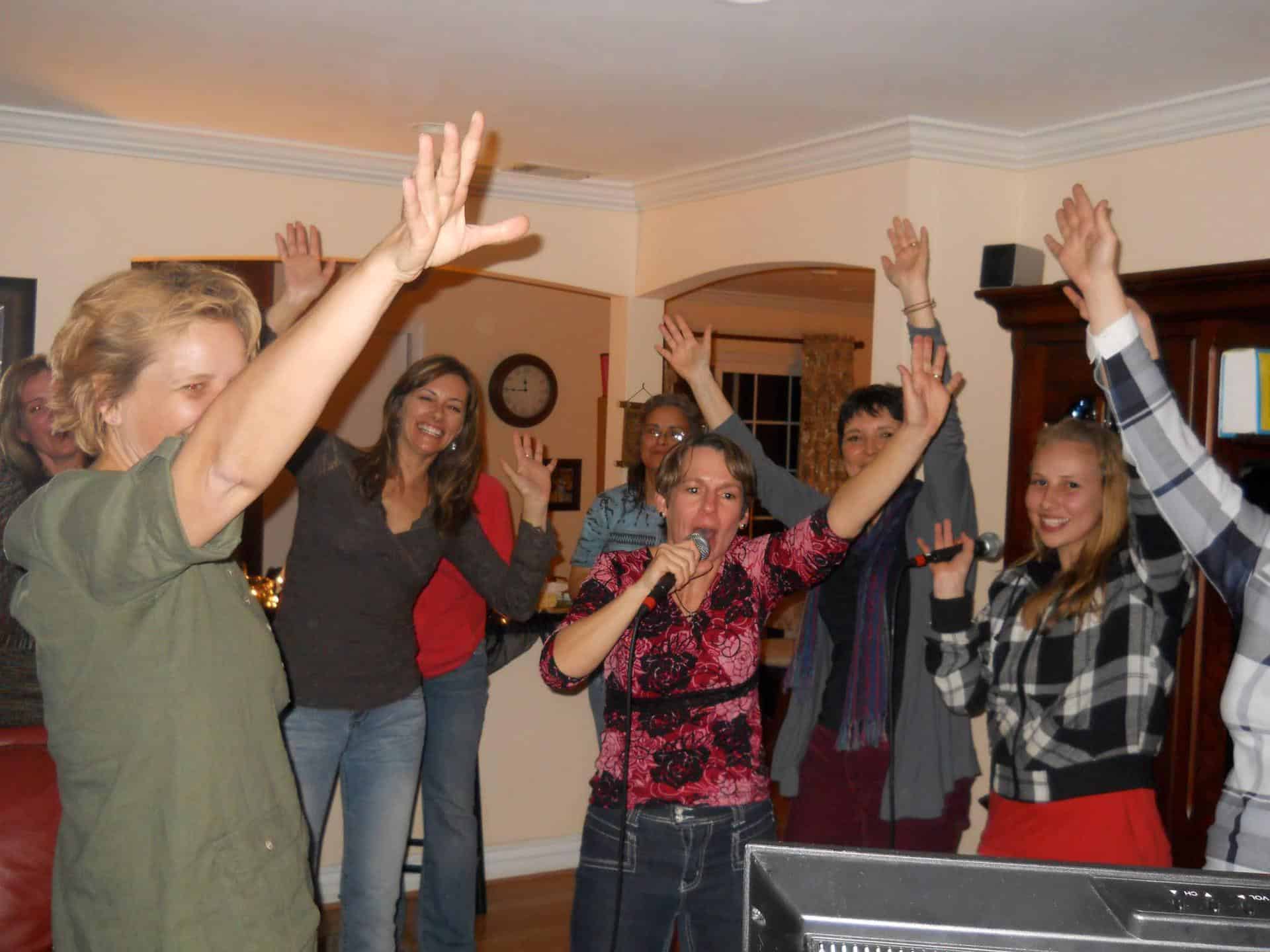 Group of friends singing karaoke at party