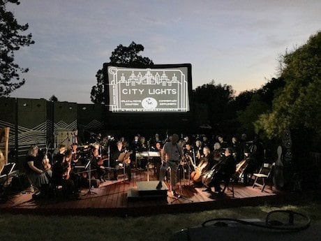 Outdoor movie playing behind an orchestra outside