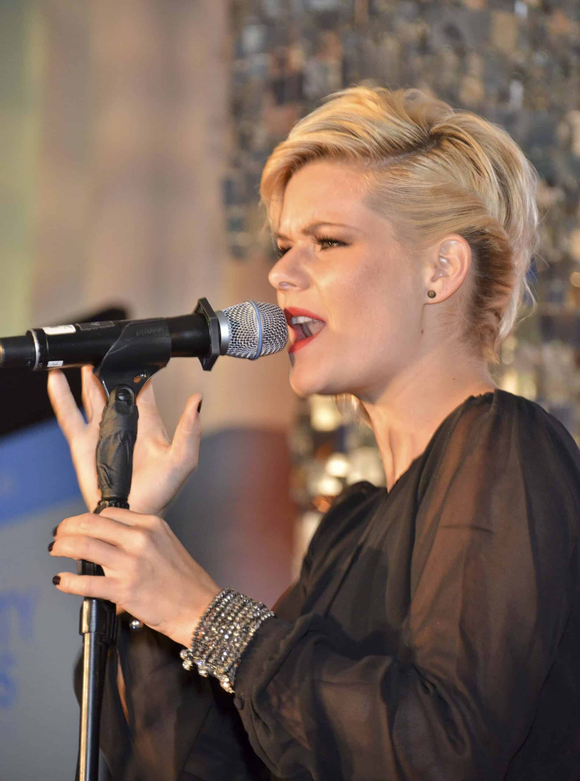 Woman singing into microphone on microphone stand